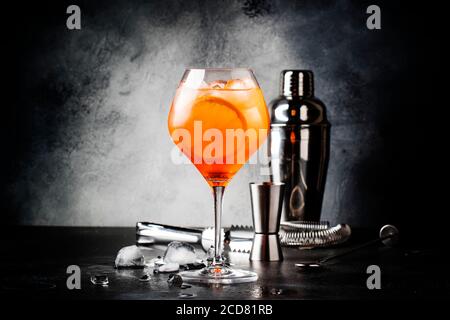 Aperol spritz cocktail in big wine glass, summer Italian low alcohol cold drink, dark bar counter background with tools, copy space Stock Photo