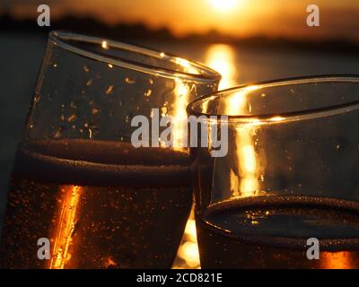 A Pair of champagne flutes filled with sparkling rose' at sunset Stock Photo