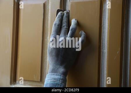 Close up of indian carpenter dirty hand doing wood finishing of home furniture using sandpaper, woodwork concept.