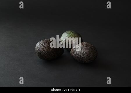 Dark green avocado fruits on a black surface Stock Photo