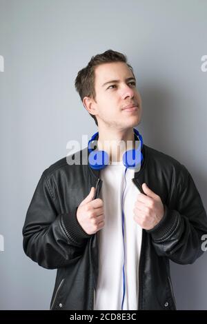 Young casual style man in black leather jacket and blue headphones. Stock Photo