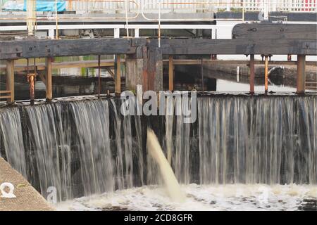 A close up view of the closed lock gates at the southern end of the Crinan Canal at Ardrishaig pier with rushing water pouring through Stock Photo