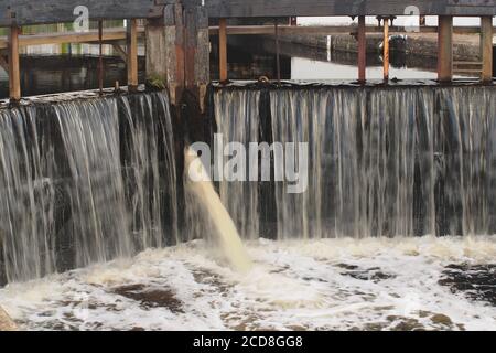 A close up view of the closed lock gates at the southern end of the Crinan Canal at Ardrishaig pier with rushing water pouring through Stock Photo
