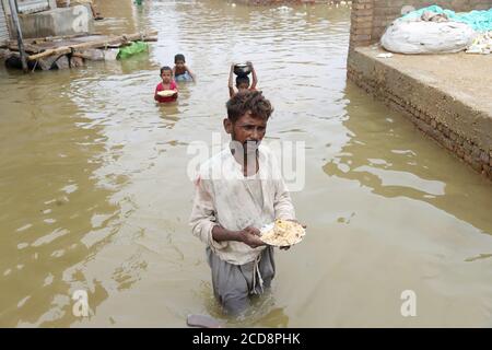 Hyderabad, Pakistan. 27th Aug, 2020. A man is carrying food and stand in water at Maher Ali colony, this are has been affected by the flood (Photo by Jan Ali Laghari/Pacific Press/Sipa USA) Credit: Sipa USA/Alamy Live News Stock Photo