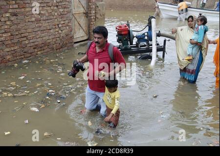 Hyderabad, Pakistan. 27th Aug, 2020. A photographer helps a child to move his to a safe place at Maher Ali colony, this are is affected by the flood (Photo by Jan Ali Laghari/Pacific Press/Sipa USA) Credit: Sipa USA/Alamy Live News Stock Photo