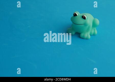 Closeup shot of a green toy frog for a bathtub on a blue