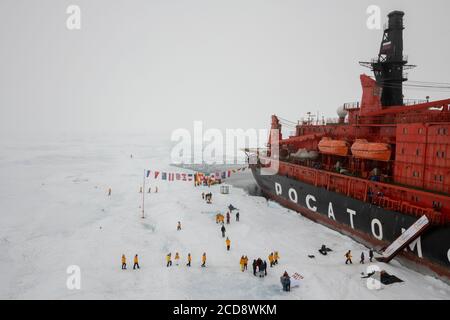 Russia, High Arctic, Geographic North Pole. 90 degrees north with 50 Years of Victory Russian icebreaker. Aerial view of adventure tourists at Pole. Stock Photo