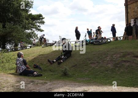 Cyclists take a break sitting on slope at Leith Hill Tower in Surrey Hills, Leith Hill, Surrey, England, UK, August 2020 Stock Photo