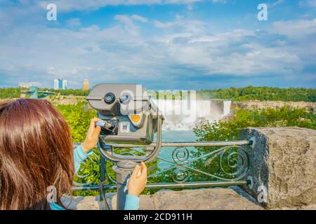 Niagara Falls, Canada, July 2015 - Blond girl holding the coin-operated binoculars overlooking Niagara Falls and state of New York across the lake Stock Photo