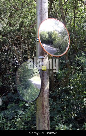 Convex mirror on a pole on a road in the UK to aid visibility at a ...