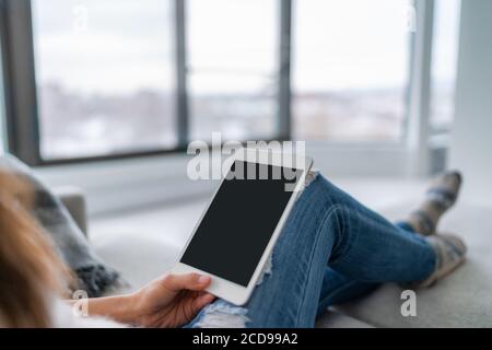 Tablet woman using pc technology device at home relaxing on sofa sitting watching video black screen or reading e-book. Tech modern lifestyle Stock Photo