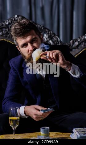 smoking gangster holding dollar bills in vintage luxury room Stock Photo