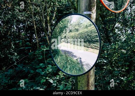 Convex mirror on a pole on a road in the UK to aid visibility at a ...