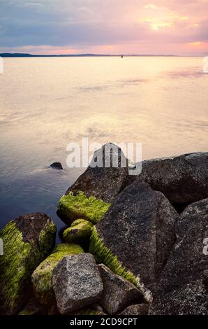 Rocky beach at a colorful sunset over the sea. Stock Photo