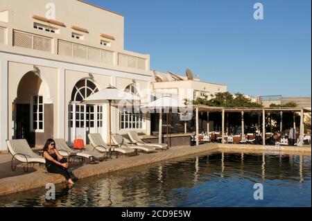 Morocco, Western Sahara, Dakhla, young Moroccan women on deckchairs in front of the swimming pool of Hotel Calipau Stock Photo