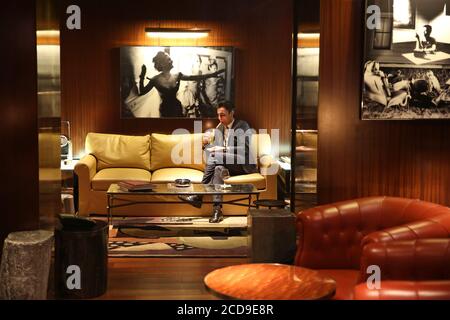 France, Paris, Royal Monceau hotel, man sitting on a leather sofa and lighting a cigar at Vinales, the private cigar club of Royal Monceau Stock Photo