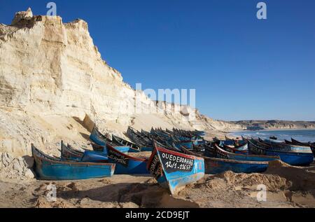 Morocco, Western Sahara, Dakhla, blue fishing boats stranded on the beach of Araiche lined with a cliff Stock Photo