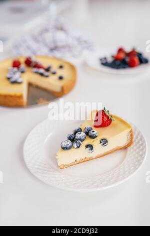 Piece of homemade Christmas winter berry cheesecake on a white plate. Stock Photo
