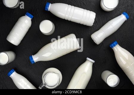 Dairy products packaging, bottles and glasses with milk on black background, top view Stock Photo