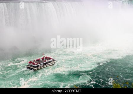 Niagara Falls, Canada, August 26 2020: Boat with tourists from Hornblower Niagara Falls boat tour moving into Horseshoe Falls mist Stock Photo