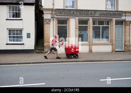 postman pushing post trolley uphill along highgate Kendal cumbria england uk Stock Photo