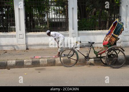 A Bangladeshi Muslim Rickshaw driver offer prayer on the street in Dhaka, Bangladesh, on March 24, 2020. Stock Photo