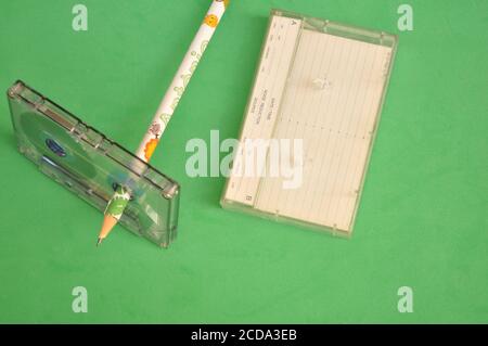 Audio cassette tape with colored pencil used to wrap the tape on green background with top view Stock Photo
