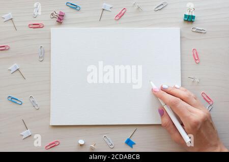 School office supplies on wooden background. Back to school concept. White board with hands for copy space. Top view ready for your design Stock Photo