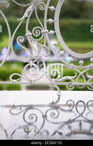 bad rainy weather, raindrops dripping on  wrought iron railing of  white house, reflection in a puddle Stock Photo