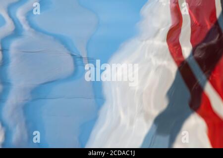 Reflection of clouds and sailboat in water Stock Photo