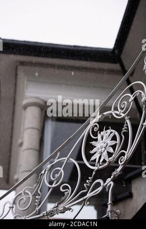 bad rainy weather, raindrops dripping on  wrought iron railing of  white house Stock Photo