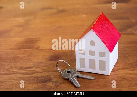 Close up of a house model and keys on a rustic wooden table. Residential real estate purchase concept. Stock Photo