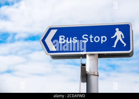 Weathered signpost pointing the way to a bus stop with cloudy sky in background Stock Photo