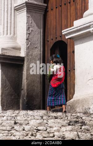 A young Quiche Mayan woman, in traditional dress, and her daughter walk toward the door of the Church of Santo Tomas in Chichicastenango, Guatemala. Stock Photo