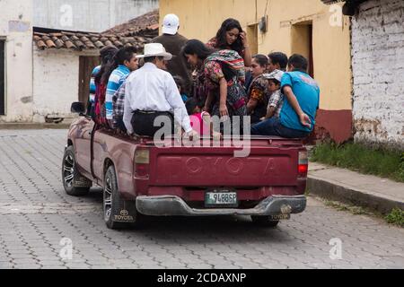 Several Quiche Mayan people, the women in traditonal dress, ride in the back of an overloaded pick-up truck for transportation in Chichicastenango, Gu Stock Photo