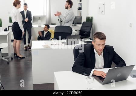One Manager in a strict dress code works while the others rest in the chill-out zone of the open space office. Workaholic concept Stock Photo