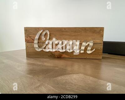 A wooden beach decoration on a table with the word ocean in cursive writing. Stock Photo