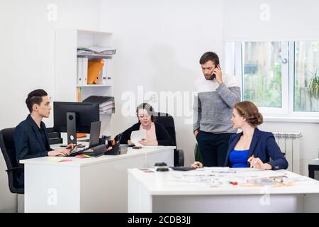 A multiracial team busy working on computers, communicating, cooperating in a coworking space. Stock Photo