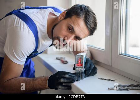 The builder measures the distance from the window with a level Stock Photo