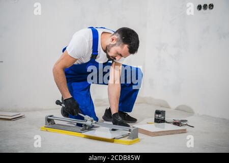 Young repairer cuts tiles with a special tool Stock Photo