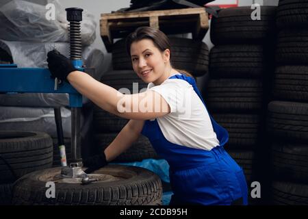 Repairwoman is using a press and looking at the camera Stock Photo