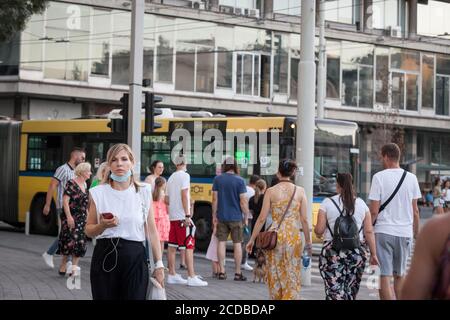 BELGRADE, SERBIA - AUGUST 13, 2020: Young woma wearing a respiratory face mask checking apps on their smartphones in the street of Belgrade, during th Stock Photo