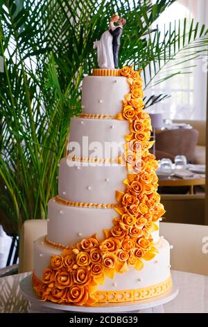 wedding cake, bride and groom couple doll on a white and golden cake Stock Photo