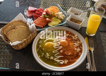 Huevos Divorciados, or Divorced Eggs, for breakfast in Mexico.  One fried egg is in red chili sauce and one in green chili salsa. Stock Photo