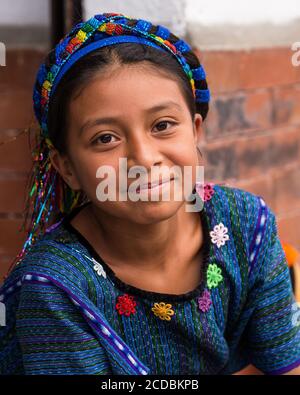 A young Cakchiquel Mayan girl in the traditional dress of San Antonio Palopo, Guatemala, including a blue woven huipil blouse and cinta or decorative Stock Photo