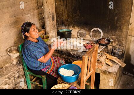 https://l450v.alamy.com/450v/2cdbkyp/a-mayan-woman-wearing-typical-dress-makes-tortillas-over-a-wood-burning-stove-in-the-kitchen-of-her-home-in-san-antonio-palopo-guatemala-2cdbkyp.jpg