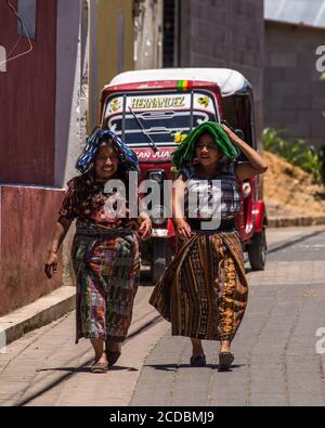 Two Tzutujil Mayan woman in traditional dress walk along a street in San Juan la Laguna, Guatemala. Stock Photo