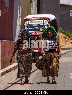 Two Tzutujil Mayan woman in traditional dress walk along a street in San Juan la Laguna, Guatemala. Stock Photo