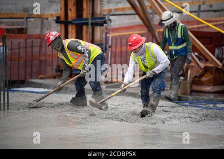 Austin, TX USA August 22, 2020: Experienced concrete crews conduct a night pour and early morning smoothing and shaping on the top floors of a high-rise parking garage in downtown Austin. Major construction projects continue unabated during the coronavirus shutdowns in Texas. Stock Photo