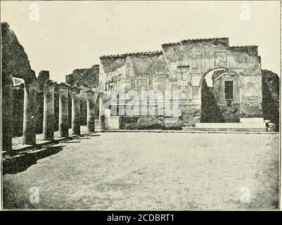 . Pompeii : its life and art . THE STABIAN BATHS J93 by two broad pillars flanked by half-columns, and carrying aroof more than five feet higher than that of the rest of thecolonnade. A similar arrangement has already been noted inthe colonnade of the temple of Isis (p. 168). The wall decoration of the court has been particularly wellpreserved on the outer wall of the rooms D and E (Fig. 85).-The surface is diversified by fantastic architectural designs intwo stories, made up of slender columns with their entablatures,. Kig. 85. — Stabian Baths: southwest corner of the palaestra, showing part Stock Photo